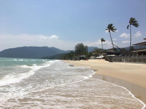 a beach with palm trees and the ocean at Khanom Beach Residence Monthly Rental Condo in Khanom
