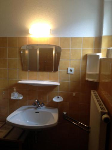 a bathroom with a sink and a light on the wall at Pension Wallnöfer in Mieming