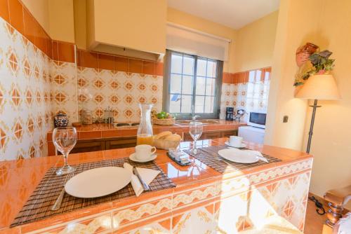 a kitchen with a counter with plates and wine glasses at Hotel Rural Sierra Tejeda in Alcaucín