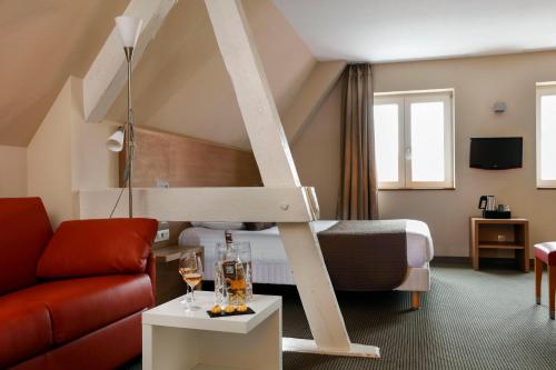 Habitación con cama y sala de estar con sofá. en La Clef des Champs - Proche Colmar, en Biesheim