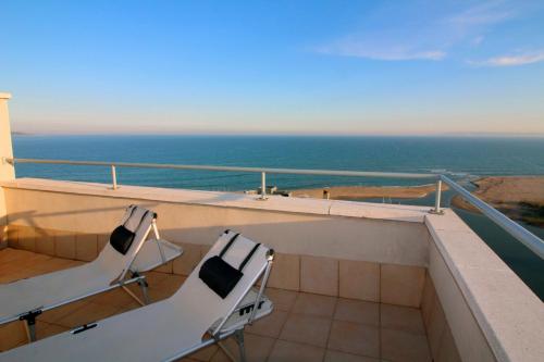 - deux chaises assises sur un balcon avec vue sur l'océan dans l'établissement Apart-rent Apartment Ancora 14º, à Empuriabrava
