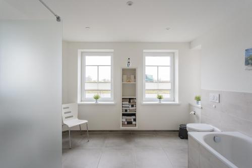 a white bathroom with a sink and a toilet and two windows at Familie Carstensen in Janneby