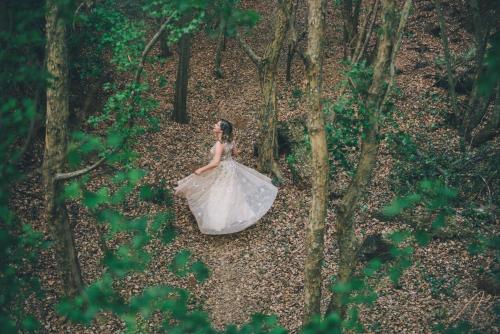 a woman in a wedding dress sitting in the woods at Whispering Pines Country Estate in Magaliesburg