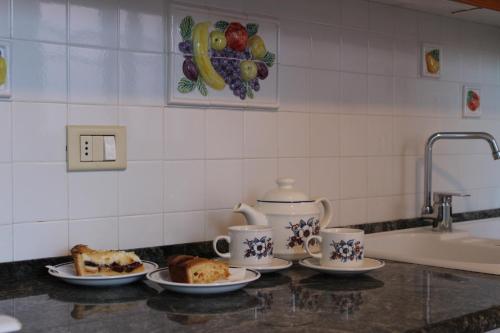 a kitchen counter with plates of food and coffee cups at Talè Talè Apartment in Marina di Ragusa
