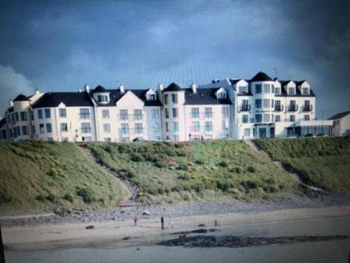 a large building on a beach with people on the sand at Beach Front Apt Portballintrae , Bushmills close to Royal Portrush Golf Club in Portballintrae