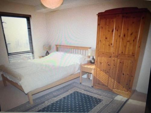 1 dormitorio con 1 cama y armario de madera en Beach Front Apt Portballintrae , Bushmills close to Royal Portrush Golf Club, en Portballintrae