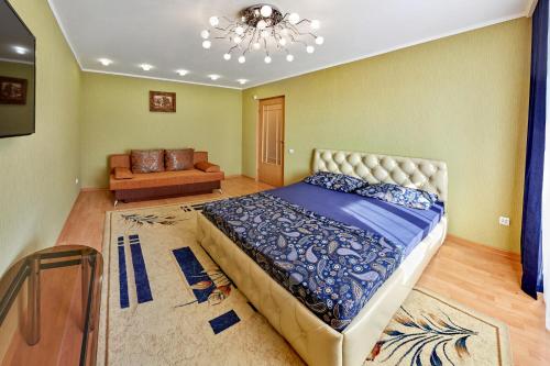 a bedroom with a large bed and a couch at Апартаменты Абажур на Максима Горького in Kurgan