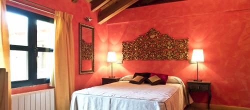 a red bedroom with a bed and two lamps at Hotel Sara De Ur in La Cabrera
