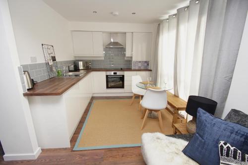cocina con armarios blancos, mesa y sillas en Apartment 3 Broadhurst Court sleeps 4 minutes from town centre & train en Stockport