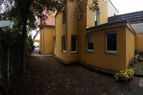 une maison jaune avec un arbre devant elle dans l'établissement FeWo Engler Bremen Neustadtstraße, à Brême