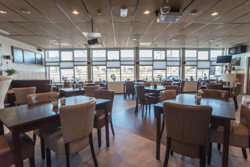 a restaurant with tables and chairs and windows at Hotel Faber in Zandvoort