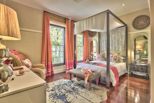 a bedroom with a canopy bed and a chair at Hout Bay Manor in Hout Bay