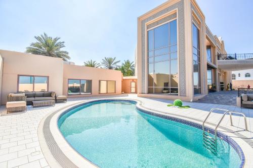 a villa with a swimming pool and a house at Hometown Apartments - Kite Palace - Lavish 7 Bedrooms villa on Kite Beach in Dubai