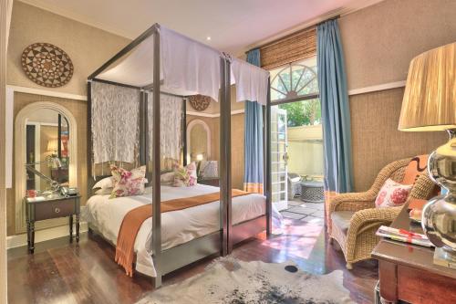 a bedroom with a canopy bed and a chair at Hout Bay Manor in Hout Bay