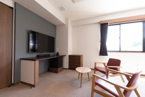 a living room with a television and a table and chairs at 宮島離れの宿 IBUKU -Miyajima Hanare no Yado IBUKU- in Miyajima
