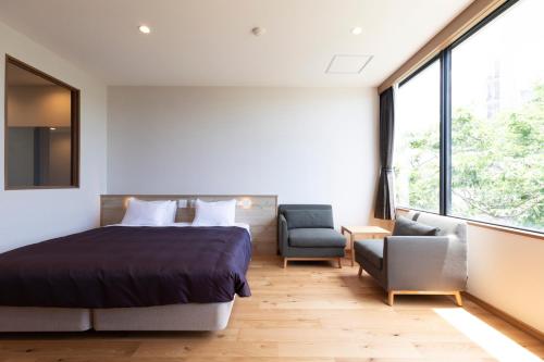 a bedroom with a bed and a chair and window at 宮島離れの宿 IBUKU -Miyajima Hanare no Yado IBUKU- in Miyajima