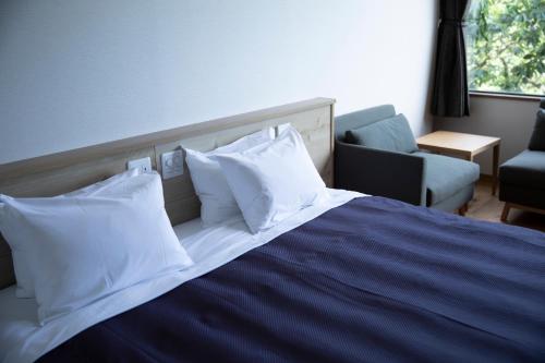 a bedroom with a bed with white pillows and a couch at 宮島離れの宿 IBUKU -Miyajima Hanare no Yado IBUKU- in Miyajima