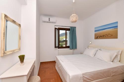 a white bedroom with a bed and a window at Villa Trifylia in Parikia