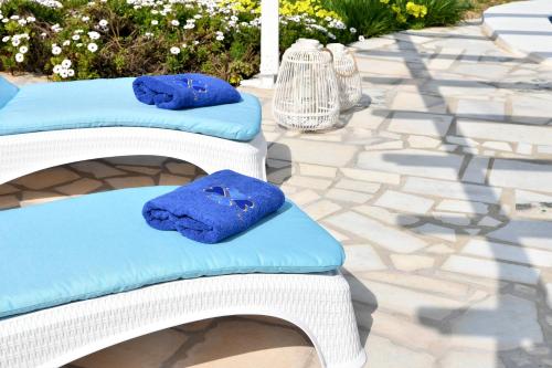 two white wicker chairs with blue cushions on a patio at Villa Trifylia in Parikia