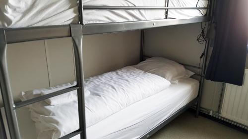 Hvammstangi Hostel في هفامستانغي: سريرين بطابقين مع ملاءات ووسائد بيضاء