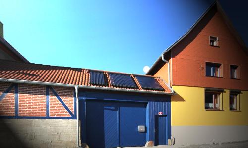 a house with a blue garage with a red roof at Hainich-Zeit in Eigenrieden