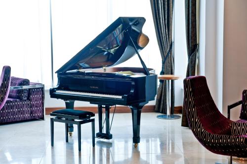 a black piano in a room with two chairs at Loughrea Hotel & Spa in Loughrea