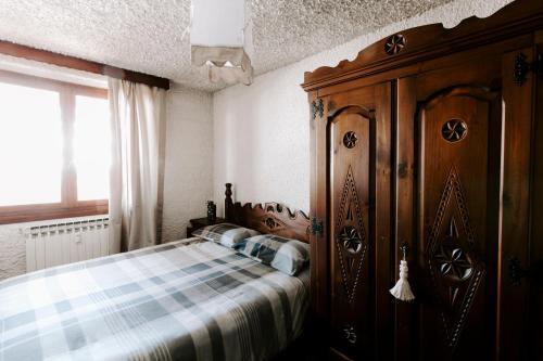 a bedroom with a bed and a wooden cabinet at Appartamento Cervino in Prato Nevoso