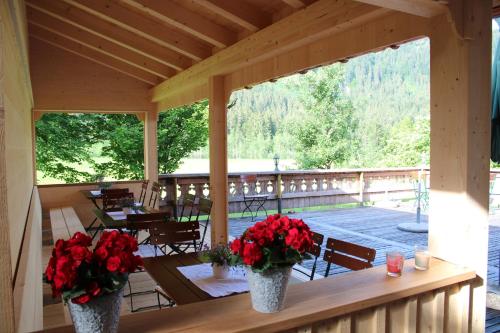 a porch with two vases with red flowers on it at Gämsle Hotel, Wirtshaus & mehr in Schoppernau