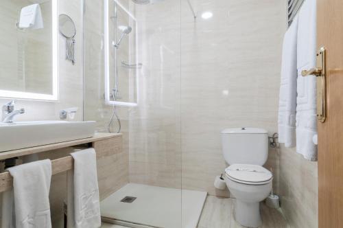 a white bathroom with a toilet and a sink at Hotel Sierra de Cazorla & SPA 3* in Cazorla