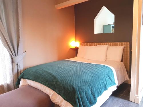 een slaapkamer met een bed met een groene deken bij Ethan Cottage in Killarney