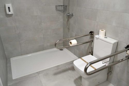 Un baño con inodoro y dispensador de papel higiénico. en Hotel Alda Estación Pontevedra, en Pontevedra