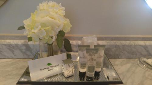 a tray with a vase with flowers and two products at Harbor House Inn in Sackets Harbor
