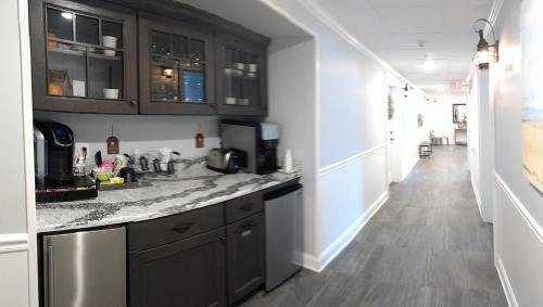 a kitchen with black cabinets and a long hallway at Harbor House Inn in Sackets Harbor