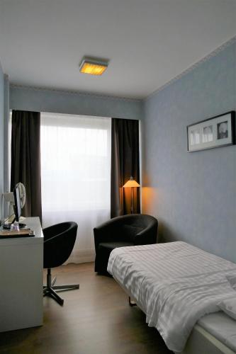 a bedroom with a bed and a desk and a chair at Linnanpiha Bed & Breakfast in Rauma