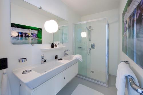 a white bathroom with a sink and a shower at Urban Residences Rotterdam in Rotterdam