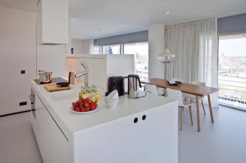 a kitchen with white counters and a table with fruit on it at Urban Residences Rotterdam in Rotterdam