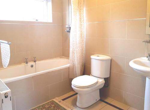 La salle de bains est pourvue de toilettes, d'une baignoire et d'un lavabo. dans l'établissement Ethan Cottage, à Killarney