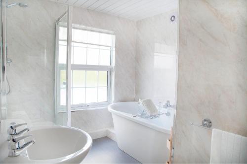 Baño blanco con bañera y lavamanos en The Shoulder Of Mutton Inn en Hamstall Ridware