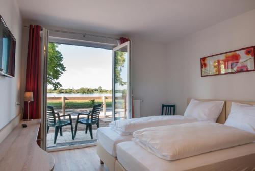 a bedroom with two beds and a balcony with a table at Hotel Elbblick in Geesthacht