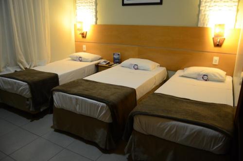 a room with three beds in a hotel room at Limeira Suítes in Limeira