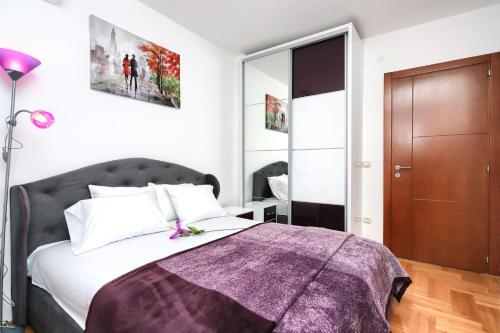 a bedroom with a bed with a purple blanket on it at Apartment Anatolia - Mina in Becici