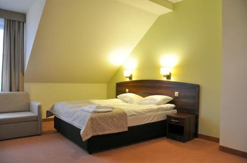 ein Hotelzimmer mit einem Bett und einem Stuhl in der Unterkunft Hotel Dudek in Mniów