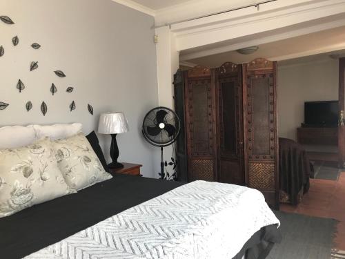 a bedroom with a bed and a fan and a television at Contemporary Stay at Giraffe Cottage in Benoni