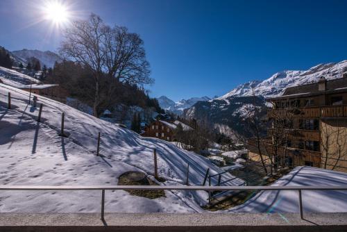 a snow covered mountain with the sun in the background at Roossi-Huus 1 in Wengen
