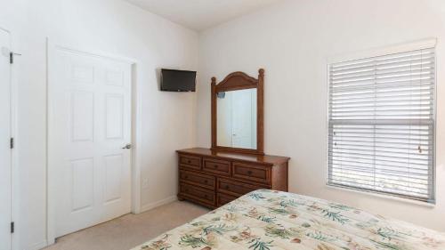 a bedroom with a mirror and a bed and a dresser at Encantada Rose - a 4 bed townhouse near Disney in Kissimmee