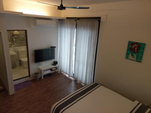 a bedroom with a bed and a flat screen tv at 5963 Turn Right B&B in Jiaoxi