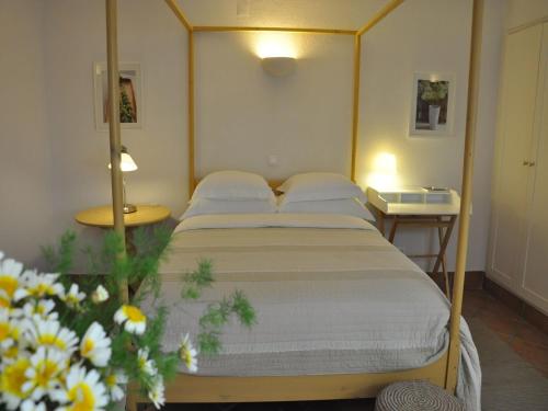 1 dormitorio con 1 cama, 2 mesas y flores en Mil Reis, en Vila Nova de Milfontes