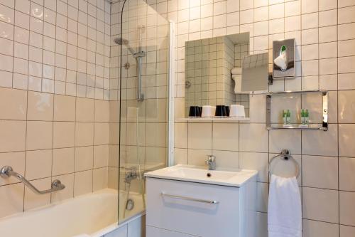 ein Bad mit einem Waschbecken und einer Dusche in der Unterkunft Hotel des Nations Saint Germain in Paris