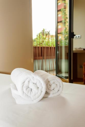 two rolled towels sitting on top of a bed at Hotel Estació in Olot