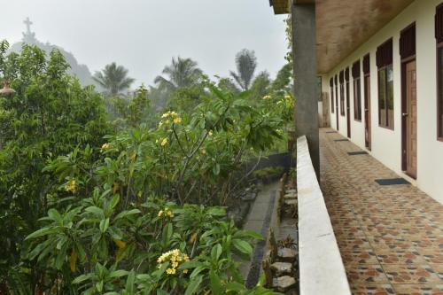 a walkway next to a building with flowers and trees at PIAS POPPIES HOTEL in Rantepao